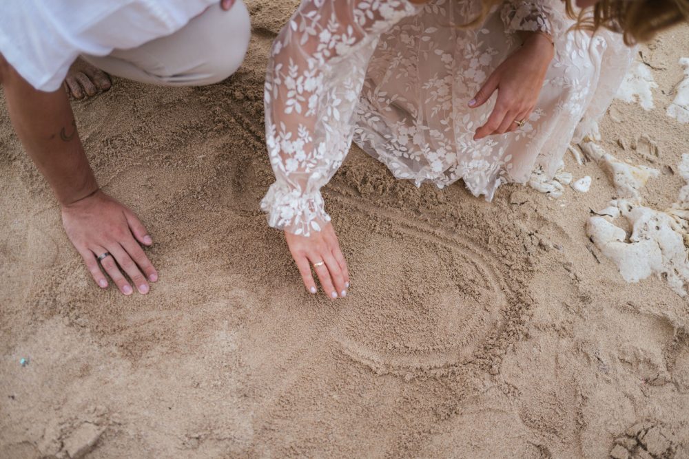 Newlyweds drawing a heart in the sand on Levan Island in Istria