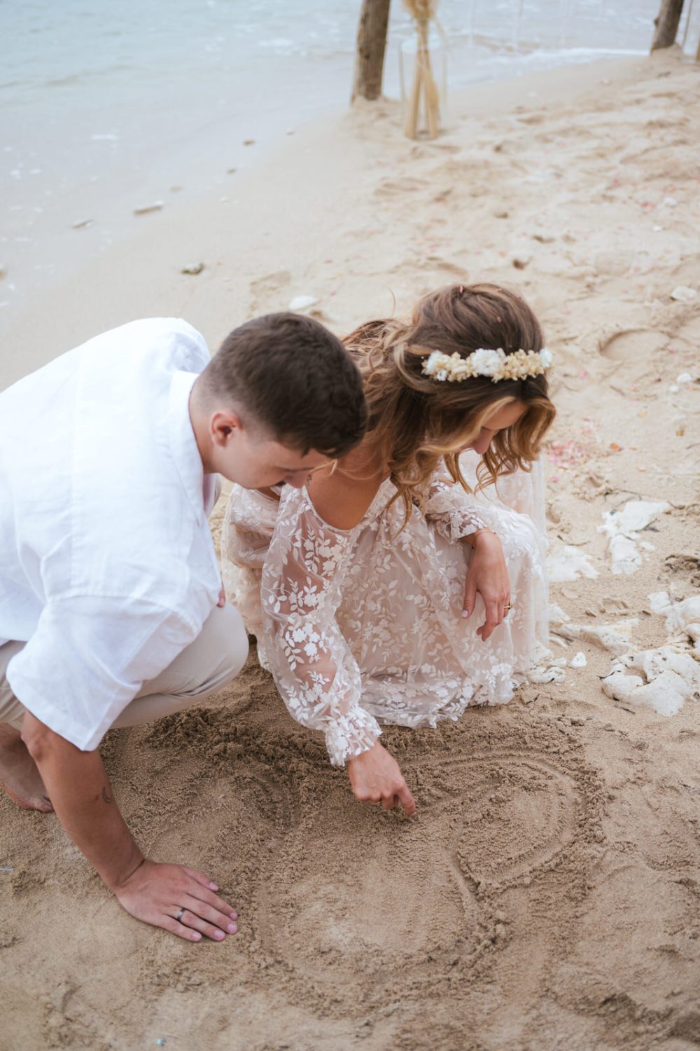 Newlyweds drawing a heart in the sand on Levan Island in Istria